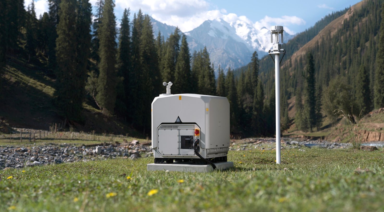 DJI Dock 4 installed on a concrete base in a mountain valley, with its weather station and antenna mast